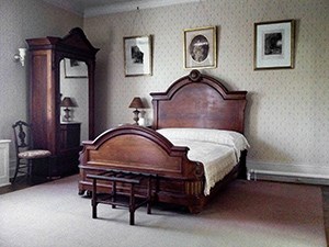 A bedroom with carved wood bed and wardrobe.