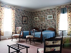 A room with floral wallpaper and a pair of twin beds.