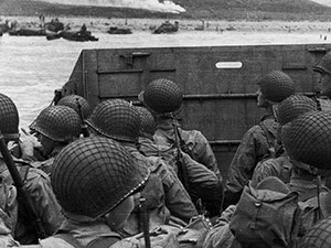 A group of soldiers on a boat heading toward a shore.