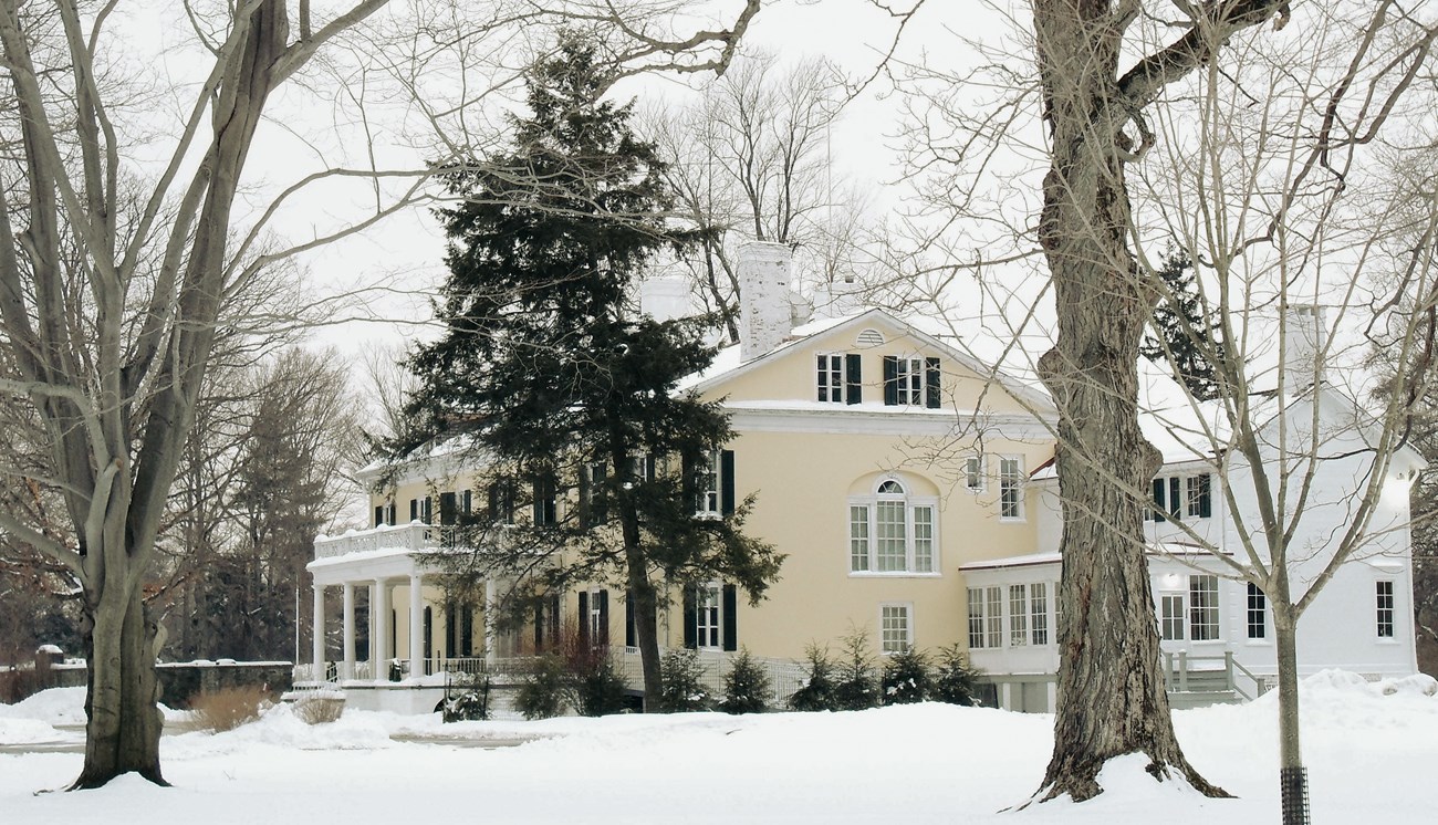 A large classical house amid a snowy landscape.