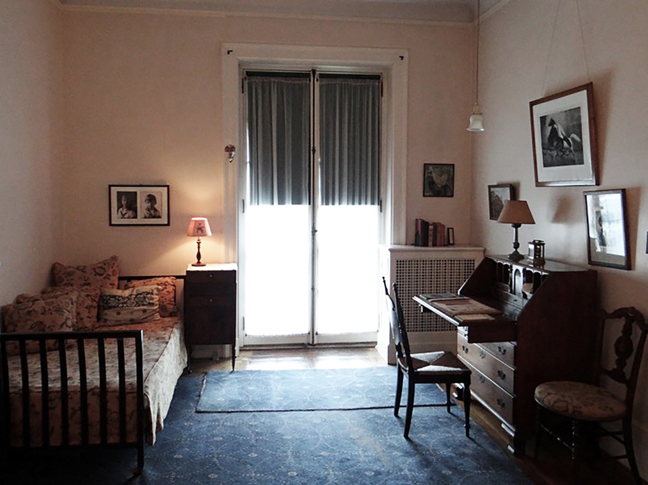 A room with double French doors, daybed, and a desk.