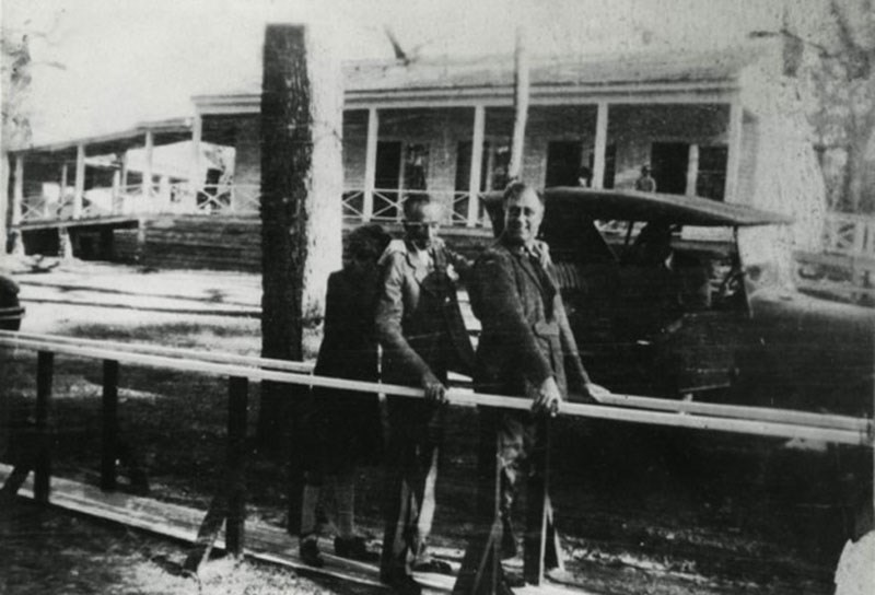 FDR, Fred Botts, and Toi walking with support of parallel bars at Warm Springs.