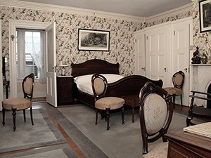 A room with dark wood bed and floral wallpaper.
