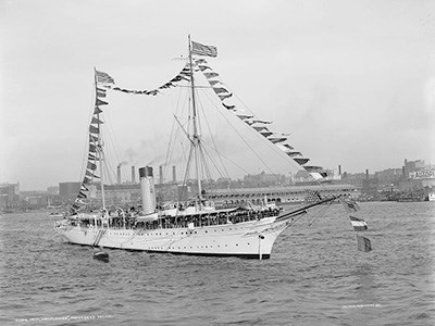 A yacht with many flags at anchor in a port.