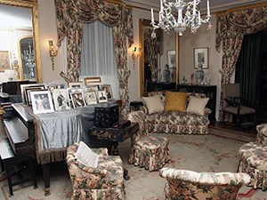 A formal room with grand piano and silver framed portraits.