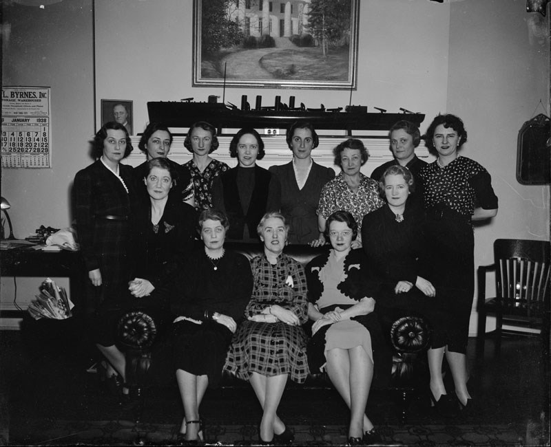 Thirteen women standing and seated in two rows posing for a photo in the White House.