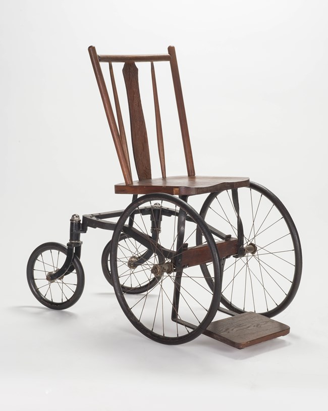A wood chair attached to a steel wheelbase.