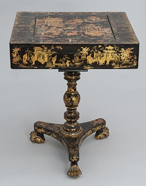 A table on tripod base painted black and decorated with Chinese scenes.