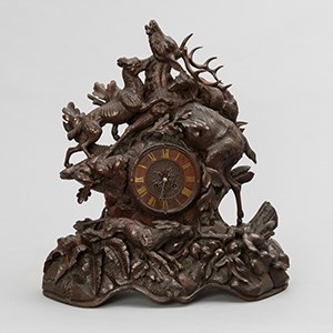 A wood carved mantle clock representing a stag under attack by three dogs.