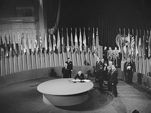 An assembly hall with the flags of many nations and delegates.