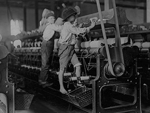two children working in a factory with large machines