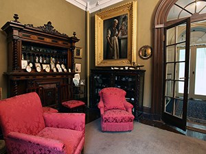 A small room with cozy furniture and gilt framed paintings.