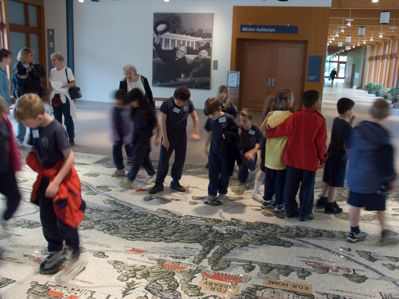 A group of adults and children viewing a mosaic map on the floor of the visitor center.