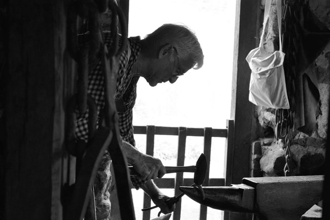 Blacksmith hammers a piece of iron on an anvil.