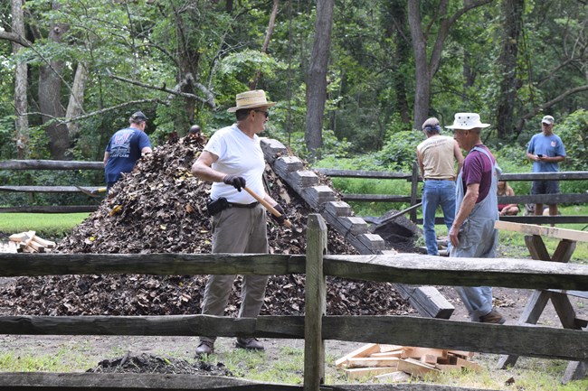 Group of colliers tend to the charcoal pile.