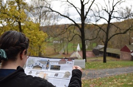 Visitor looks at brochure with historic buildings in the background
