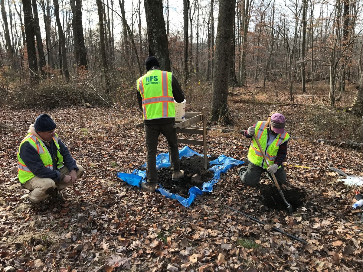 Three archeologists working at a dig site at Hopewell Furnace National Historic Site.