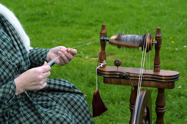 Hopewell Furnace Living History volunteer demonstrating how wool is spun