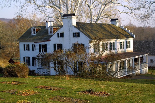 White stone house with green shudders.