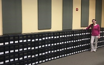 Homestead Museum Technician stands next to organized boxes of Dempster Records.