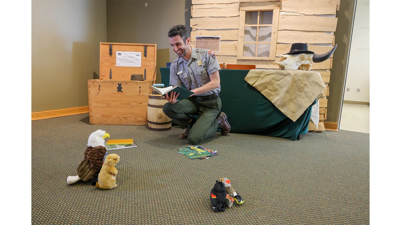 Read With A Ranger Ranger practices reading a book to stuffed animals