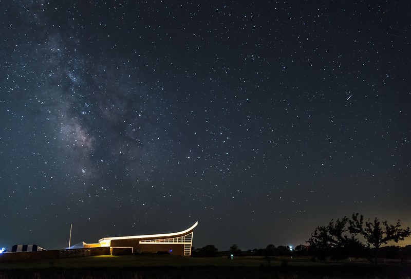 A lit building stands against a starry night sky.