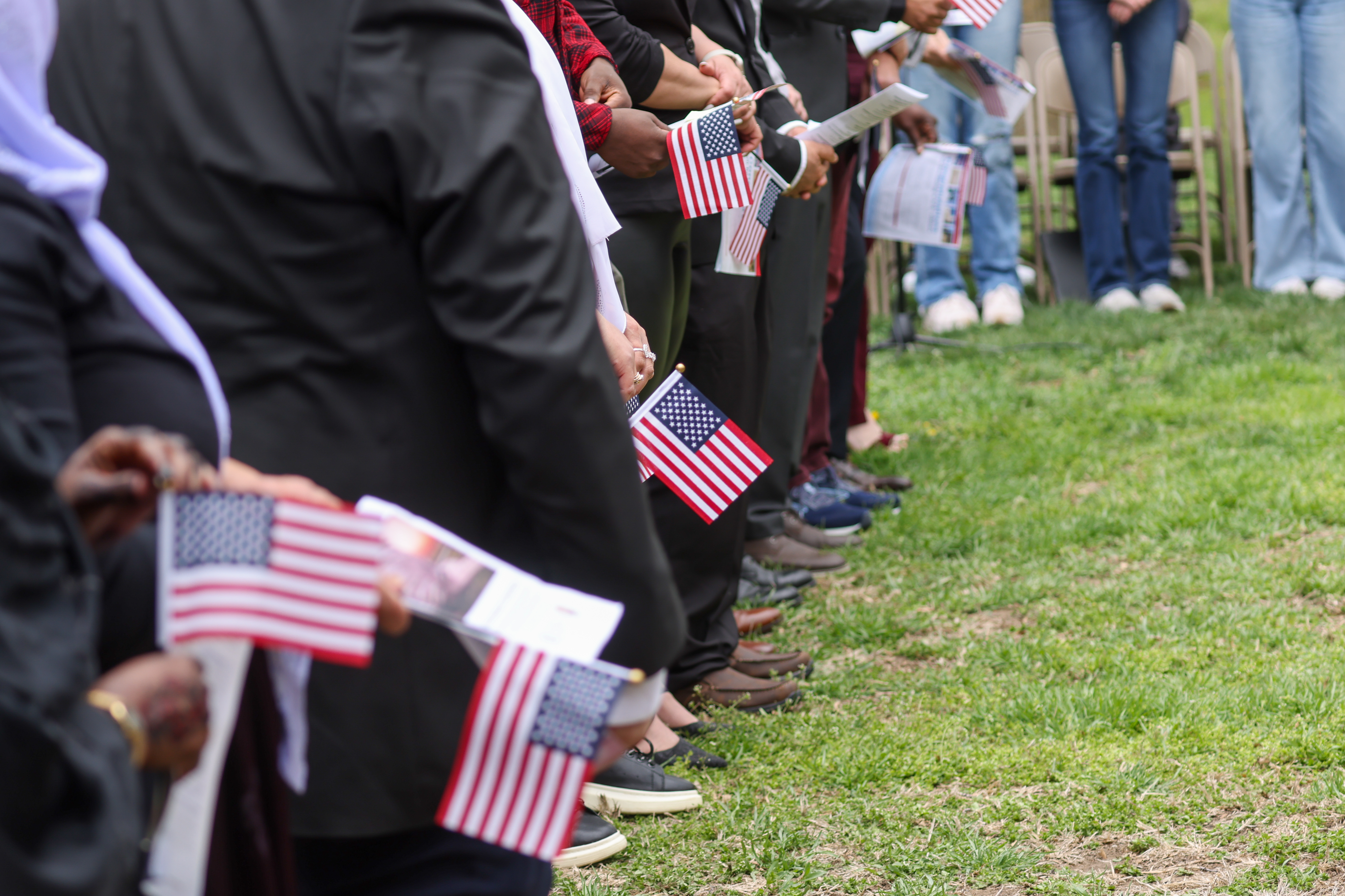 Flag Day Naturalization Ceremony A row of individuals stand in line holding small US flags and documents.