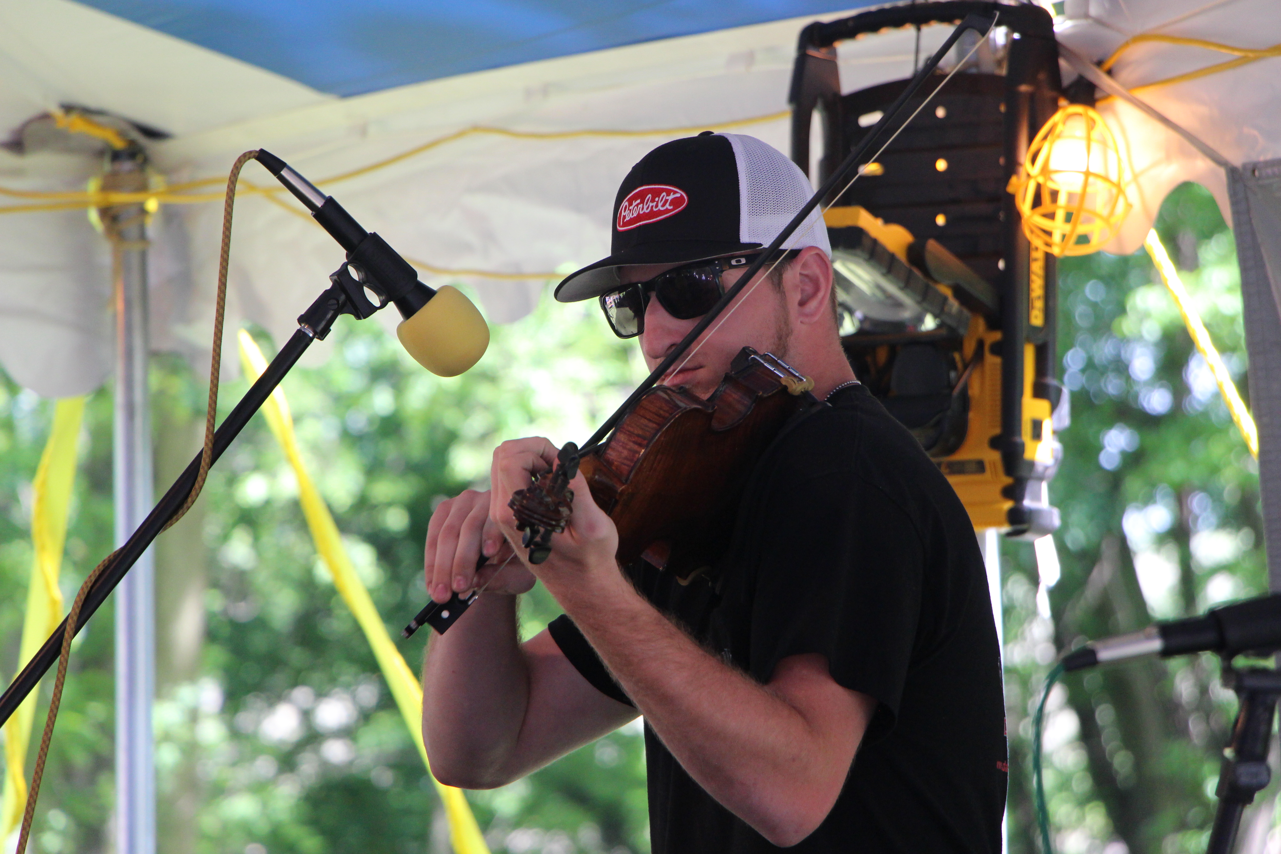 A man stands at a microphone playing the fiddle.