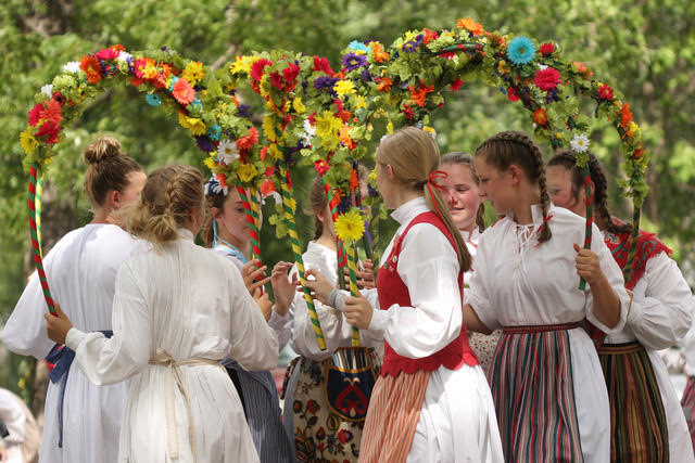 Group of young girls in a circle carrying flower arches