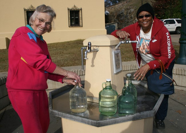 Two women filling up jugs at a water station