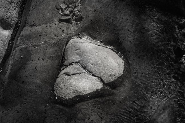 Black and white photo of a rock in a creek