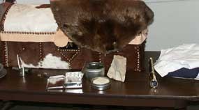 Hide-covered trunk with beaver fur laying over it and some early 1800s period items laying on table Hide-covered trunk with beaver fur laying over it and some early 1800s period items laying on table