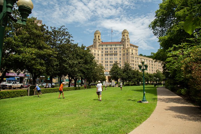 Arlington Lawn on a sunny summer day with people playing catch with the Arlington Hotel towering in the background.