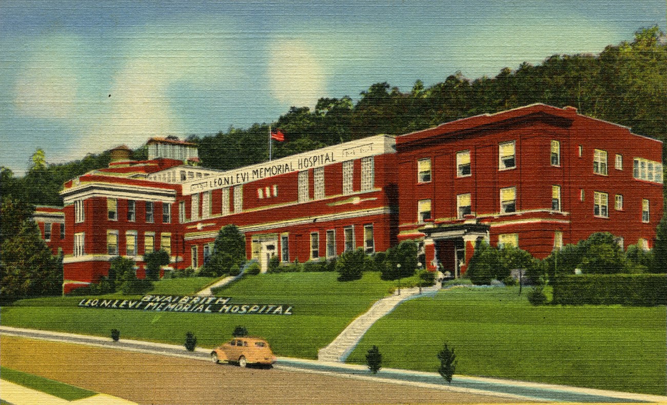 Red building on hillside with yellow car in road in front of it