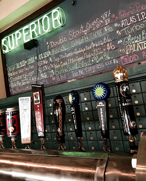 Color image of the interior of the Superior Bathhouse Brewery showing beer dispensers and a neon lighted sign saying Superior.