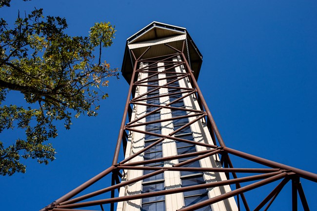 The mountain tower is over ten stories high with a staircase and elevator going up to the top where there is an enclosed lookout are and an exposed balcony over top. It's a very geometric shaped tower its many sharp edges and angles.
