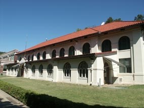 color photo of the Hale Bathhouse, a two story buff colored stucco building with red tile roof. The Mission Revival style includes arched windows all along the front of the building.