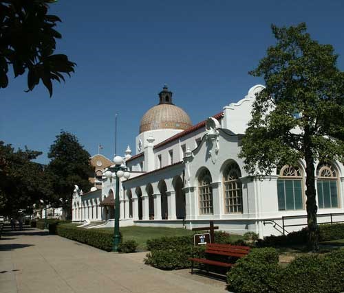 Quapaw Bathhouse from the south end on a sunny day with a deep blue sky. The Quapaw Bathhosue is a white stucco structure with a red tile roof and a mosaic tiled dome in the center of the roof. Quapaw Bathhouse from the south end on a sunny day with a deep blue sky. The Quapaw Bathhosue is a white stucco structure with a red tile roof and a mosaic tiled dome in the center of the roof.