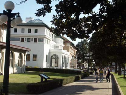 View of Bathhouse Row, looking south from just above the Maurice Bathhouse. It is a sunny afternoon with the Southern magnolia trees on the street side shading walking visitors. View of Bathhouse Row, looking south from just above the Maurice Bathhouse. It is a sunny afternoon with the Southern magnolia trees on the street side shading walking visitors.
