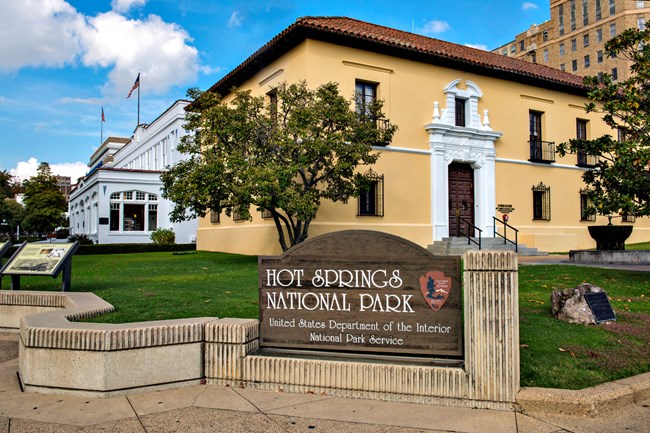 NPS entrance sign for Hot Springs National Park with the Admin building in the background.
