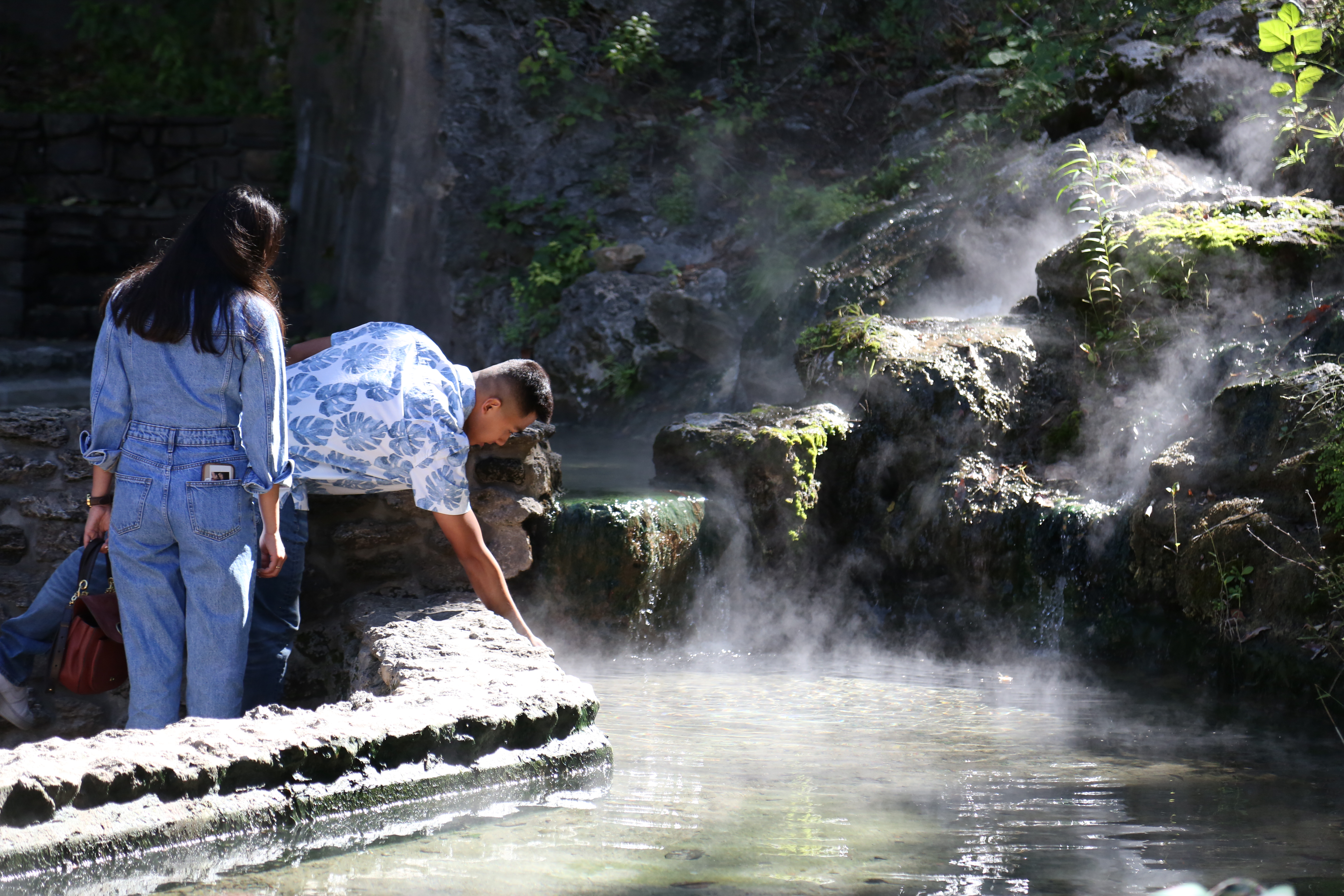 Two people look at a pool of steaming water.