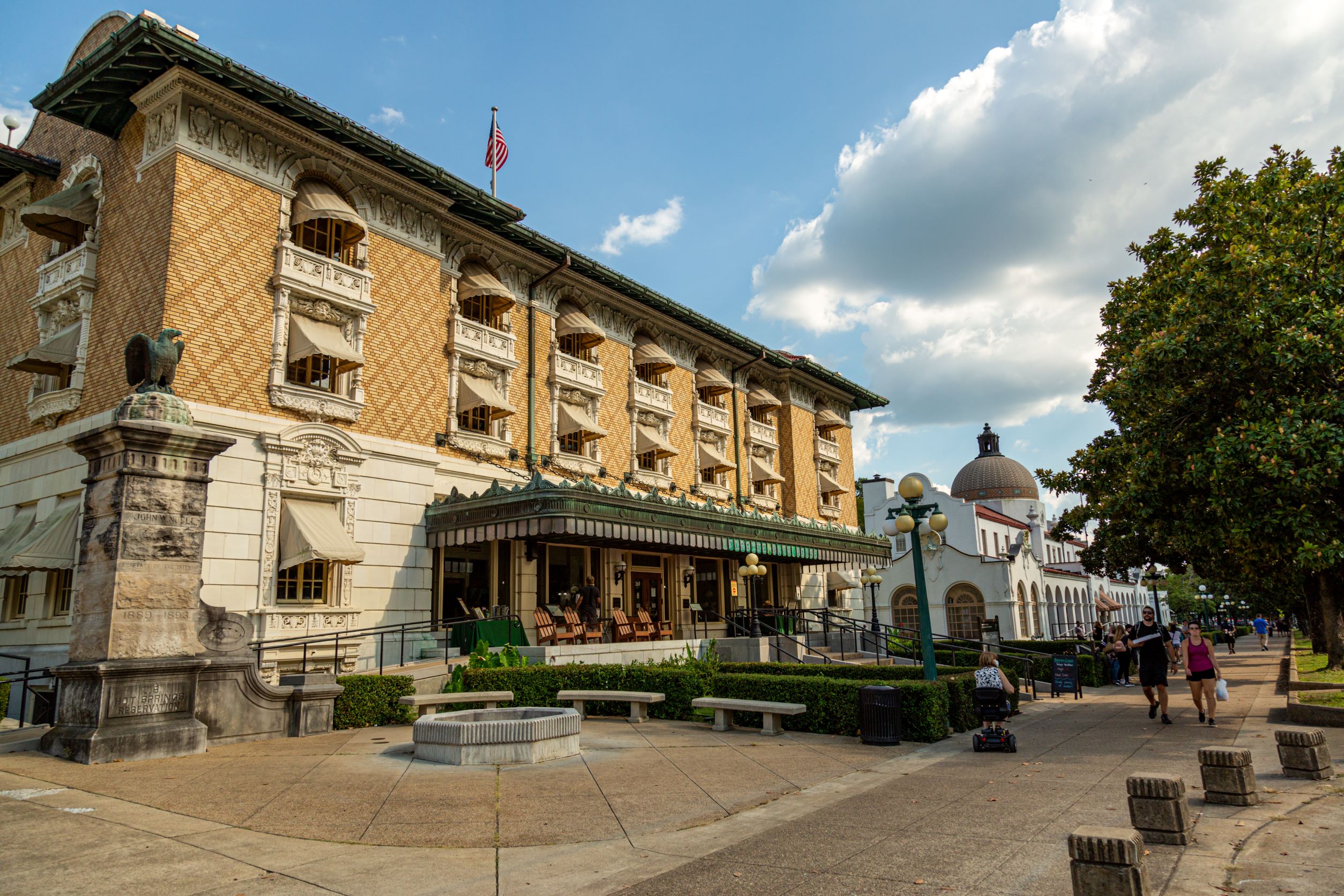 An ornate 3 story building with patterned brick and a copper awning stands tall in the bright sunlight.