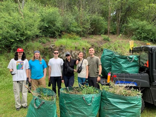 A group poses in front of bags of invasive plants