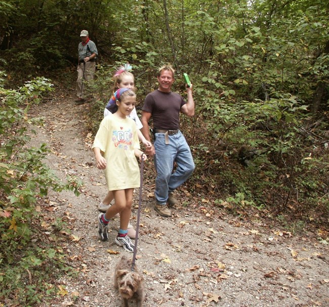 two girls and a man hiking the trail with their dog