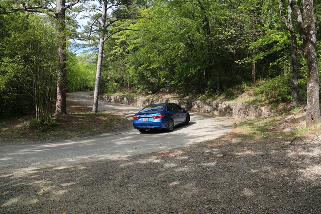A blue Honda Civic drives up the forested winding road on Hot Springs Mountain Drive.