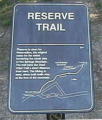 color photo of Reserve Trail trailhead sign. Sign is made of dark brown metal with gold lettering and map of trail color photo of Reserve Trail trailhead sign. Sign is made of dark brown metal with gold lettering and map of trail