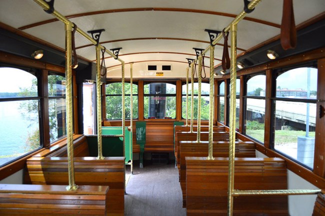 Interior view of the Hot Springs Trolley. Wooden features and brass handles decorate the inside.