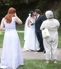 bride and groom kiss as bridesmaid and woman look on bride and groom kiss as bridesmaid and woman look on