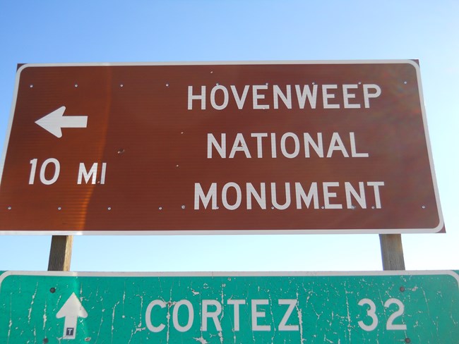 large brown sign with words "Hovenweep National Monument, 10 mi" and arrow