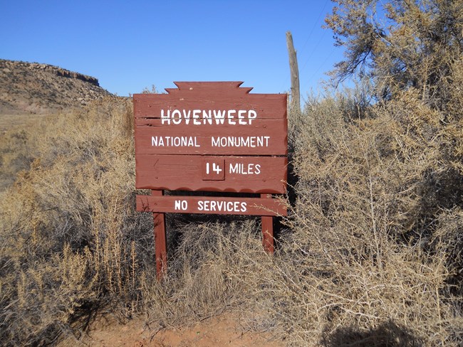 a wooden road sign with directions to Hovenweep National Monument
